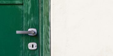 green wooden door beside white wall