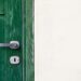 green wooden door beside white wall